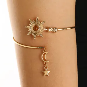 Primo piano del bracciale da braccio dorato vintage con ciondoli a sole e stella.