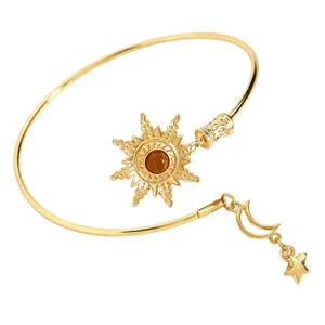 Dettaglio bracciale da braccio dorato con pendente sole vintage, pietra marrone e luna.