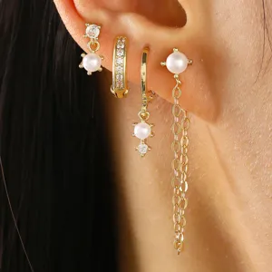 Detailopname van gouden oorbellen met parels en sprankelende zirkonia stenen voor damesstijl.