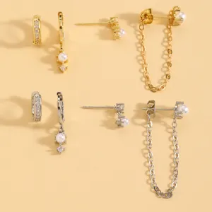 Detailed shot of a stylish earring set featuring gold and silver hoops, pearl studs, and chains.