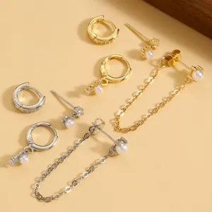 Close-up detail shot of gold and silver tone zirconia pearl hoop and chain stud earrings.