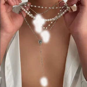 Primer plano detallado de collares de perlas y cadenas plateadas con colgantes de cruz.