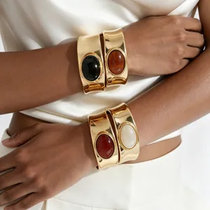 Chunky gold-tone wide cuff bracelets with striking oval colored gemstones for daily fashion.