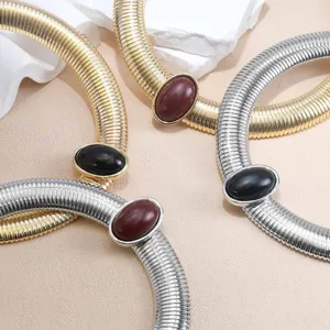 Close-up detail of chunky metal snake chain choker necklace with elegant oval gemstone.