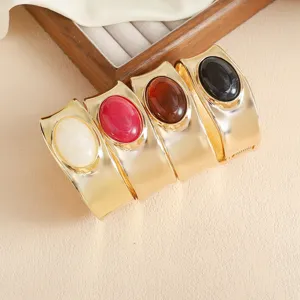 Wide metal cuff bracelets featuring elegant oval gemstones in various stylish colors.