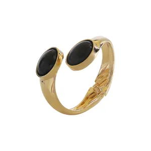 Gold open cuff bracelet with dual oval black stone ends, modern chic jewelry detail view.
