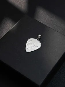 Stainless steel guitar pick pendant with music note engraving, detailed view showing metallic texture.