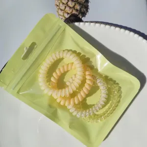 Detailed view of colorful phone cord hair ties in green bag on plate, cute and durable.