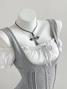 Detail shot of women's grey color-block patchwork short sleeve top with bow and cross necklace.