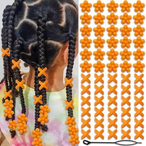 Detailed view of orange acrylic hair beads and X-shaped clips with a pulling tool for braids.