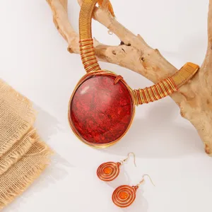 Vue détaillée du collier pendentif en pierre rouge et boucles d'oreilles sur branche.