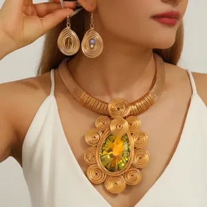 Closeup of oversized handmade gold wire woven necklace and teardrop earrings with crystal.