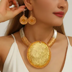 Ensemble collier et boucles d'oreilles tendance dorés avec grand pendentif rond texturé.