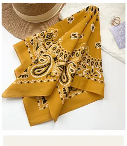 Detail shot of retro yellow paisley cotton square scarf, soft fabric texture close up view.