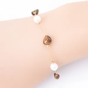 Close-up detail of a delicate 18k gold plated bracelet featuring pearls and natural stones.