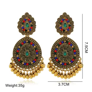 Detailed view of antique gold ethnic teardrop earrings with colorful rhinestones and tassels.