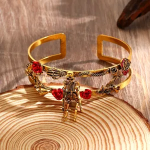 Dettaglio ravvicinato del bracciale rigido aperto vintage dorato punk con scheletro e rose.