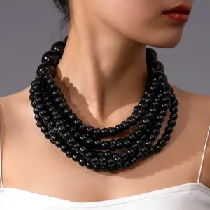 Gros plan détaillé d'un collier de perles en bois noir multicouche avec texture artisanale.