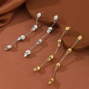 Detailed view of punk retro style multi-skull tassel long earrings in silver and gold.