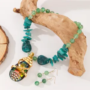 Detailed view of green crystal gemstone pendant necklace and matching earrings jewelry set.