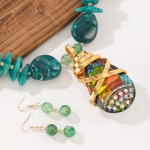 Crystal teardrop pendant necklace and matching earrings detail, colorful fashion jewelry set.