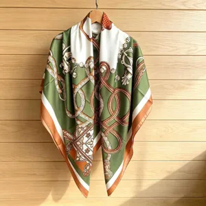Detailed view of luxury style printed square silk scarf, elegant green and orange accessory.
