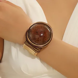 Primo piano del bracciale rigido largo con grande gemma in resina e tessitura in filo.
