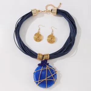 Set di gioielli con collana con ciondolo in resina blu e orecchini a spirale.