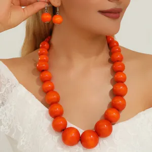 Gros plan détaillé de collier statement en perles de bois orange bohème et boucles assorties.