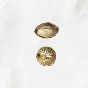 Gros plan de l'arrière de deux broches de mode en alliage avec fermoir à épingle et texture.