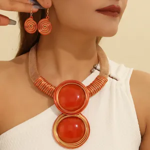 Close-up of geometric orange resin statement necklace and earrings set with aluminum wire weaving.