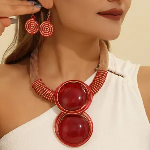 Close-up detail of red and gold wire woven statement necklace and matching spiral earrings.