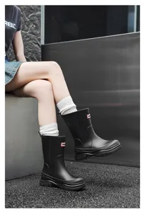 Close-up view of black mid-calf rain boots showing texture and fit with cozy white socks.