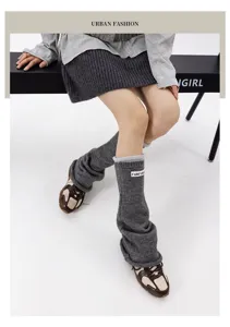 Detail shot of grey knitted leg warmers for women, featuring rolled edges and cloth label.