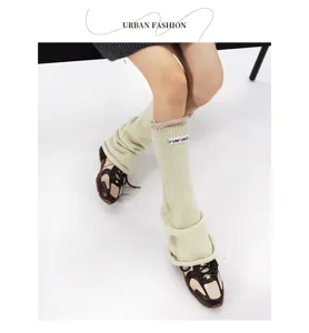 Detailed view of knitted leg warmers with fabric label, winter color-block style socks.