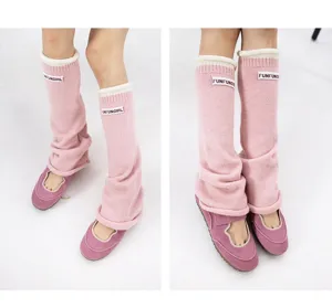 Pink knit leg warmers with rolled edges and stylish fabric label for women winter fashion.