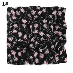 Vue détaillée du foulard carré en mousseline noire avec un imprimé floral très élégant.