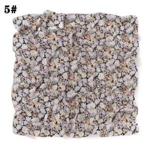 Détail de foulard carré en mousseline avec un délicat motif floral multicolore et texture.