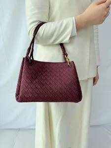 Detailed view of handmade woven shoulder handbag in burgundy, showcasing classic design texture.