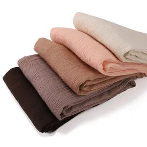 Details of soft crinkled linen scarf stacked in multiple earthy colors for daily styling.