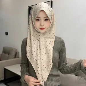 Vue détaillée d'un foulard triangulaire rétro à pois porté comme coiffe élégante.