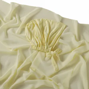 Vue détaillée de bonnet à nouer en modal jaune pâle et écharpe en mousseline.