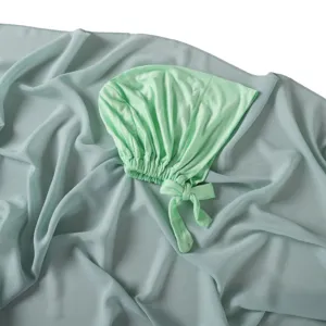 Vue détaillée du bonnet à nouer en modal uni et de son écharpe longue en mousseline.