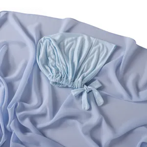 Vue rapprochée détaillée du bonnet à nouer en modal bleu clair et de l'écharpe en mousseline.
