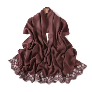 Detailed view of glossy pearlescent scarf with delicate white floral embroidery and scalloped edge.