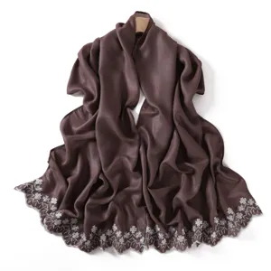 Detailed view of a lustrous brown scarf featuring exquisite white floral embroidery along edges.