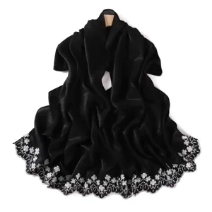 Close-up detail of black shiny shawl with exquisite white floral embroidery hem.