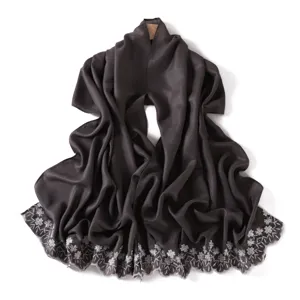 Close-up detail of dark glossy long scarf featuring exquisite white floral embroidery edge.