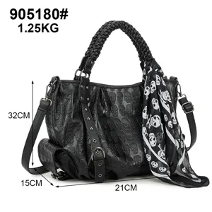 Vue détail de sac à main punk en cuir noir à crânes gaufrés, poignée tressée et foulard tête.
