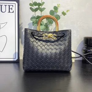 Detailed view of black woven leather handbag featuring metal knot handle and exquisite texture.